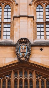 Detailed facade of a historic building at Oxford University, featuring old architecture and emblem.