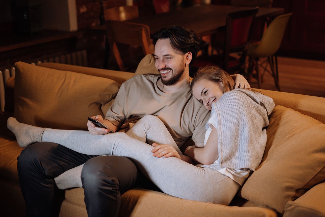 Deutsches Fernsehen in der Schweiz empfangen — ARD, ZDF, SRF und türkische Sender in einer App, ohne VPN. Paar entspannt zuhause auf dem Sofa am Abend