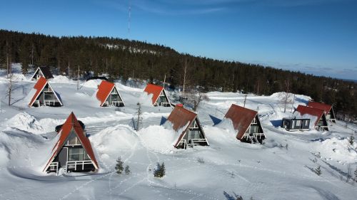 Free Aerial view of A-frame cabins in snow, surrounded by Finnish forest in winter. Stock Photo