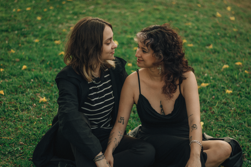 Free A couple sitting close on grassy field, sharing a tender moment outdoors. Stock Photo