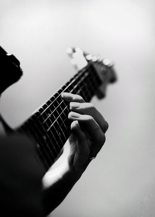 Free Monochrome image of a guitarist's fingers plucking strings on an electric guitar, capturing musical expression. Stock Photo