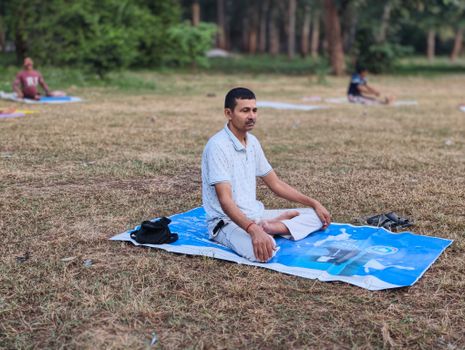 Man practicing meditation in a peaceful outdoor park setting, enhancing mindfulness and relaxation.
