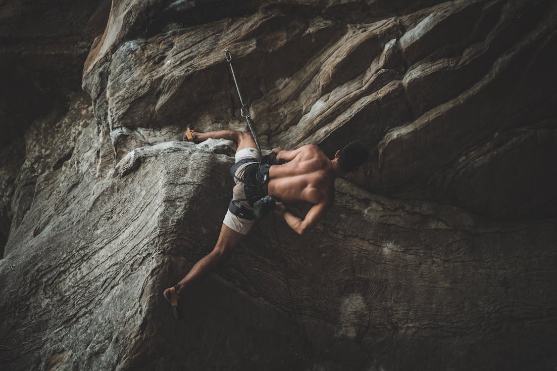 Free Strong male climber hanging on rope in ravine Stock Photo