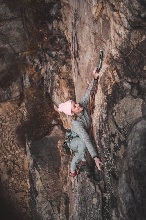 Strong woman climbing up rocky mountain with rope