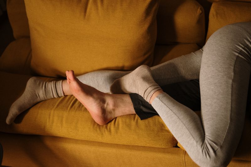 A couple snuggling together on a comfortable yellow sofa at home.
