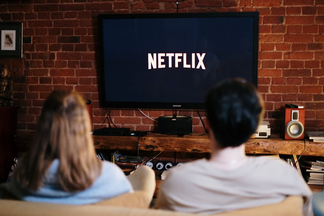 Free Man and Woman Sitting on a Couch in Front of a Television Stock Photo