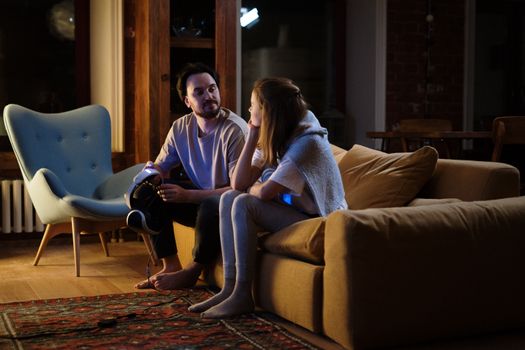 A couple enjoys a relaxing evening at home, using VR goggles on the couch.
