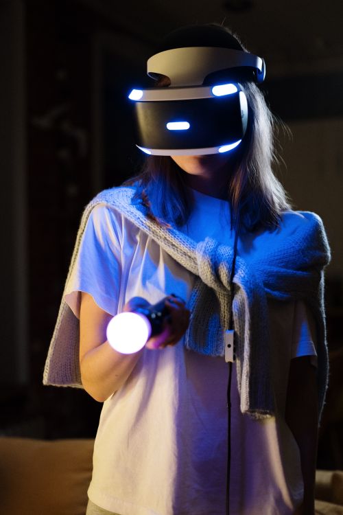 Free Woman enjoying a virtual reality gaming session with VR headset and controller. Stock Photo