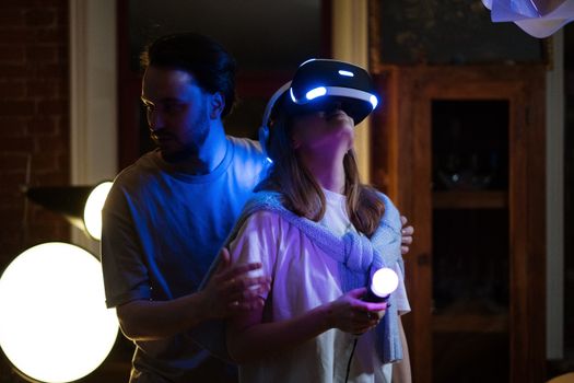 A couple experiences virtual reality gaming with headsets and controllers in a cozy home setting.
