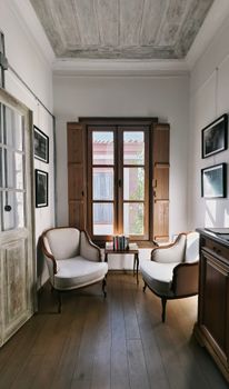 Bright and inviting sitting area with two chairs and a wooden window in Ayvalık, Türkiye.