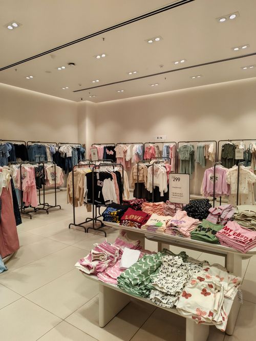 Free Bright retail store showcasing neatly arranged clothing and accessories on racks and tables. Stock Photo