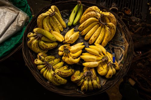 Free Overhead view of ripe bananas in a wicker basket at a street market in Mumbai, India. Stock Photo