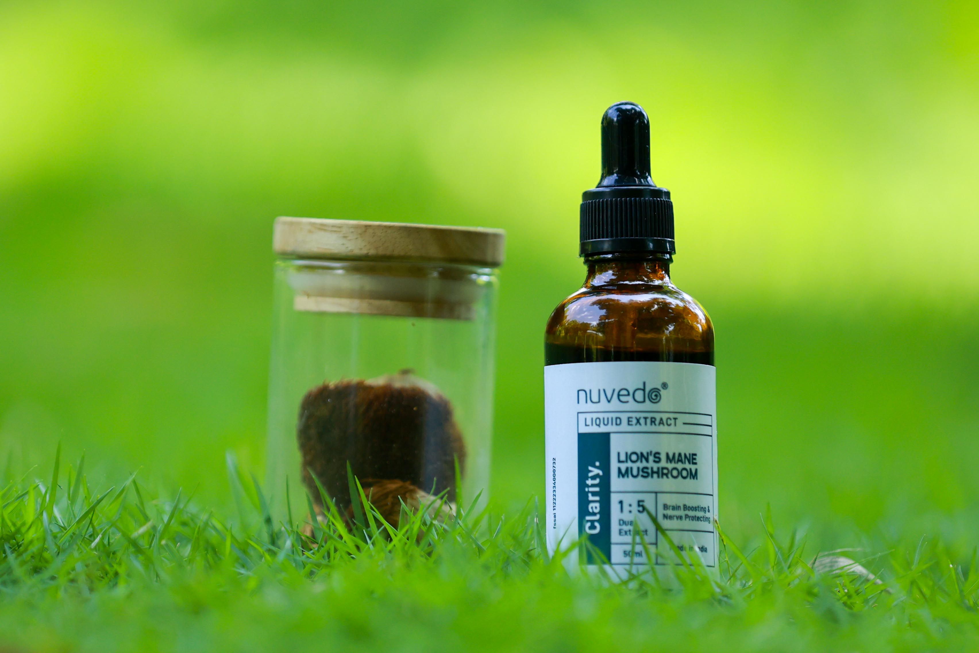A bottle of Lion's Mane Mushroom liquid extract and jar on a grassy field, emphasizing natural supplements.