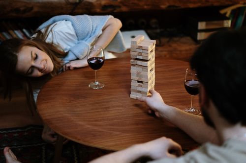 Free A couple enjoying a cozy evening playing Jenga with glasses of red wine at home. Stock Photo
