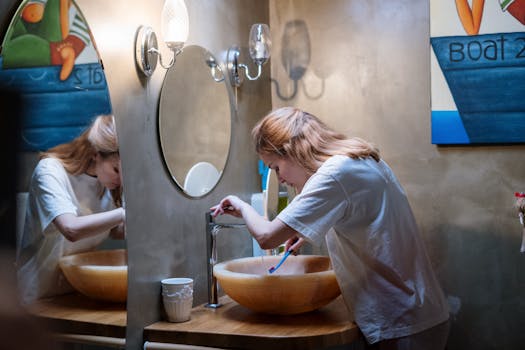 A woman brushing her teeth in a cozy, modern bathroom with warm lighting and artistic decor.