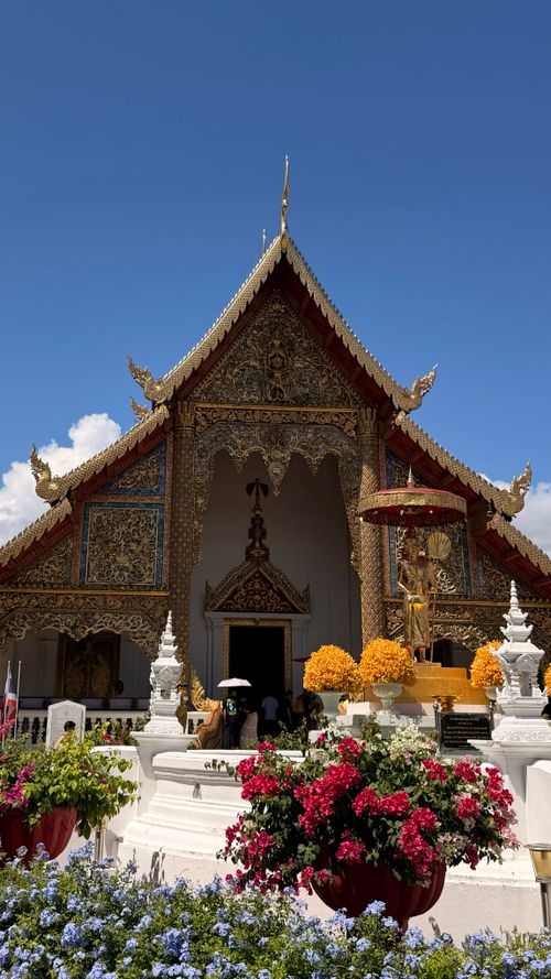 Free Intricate Wat with floral foreground in Chiang Mai, Thailand, under a clear blue sky. Stock Photo