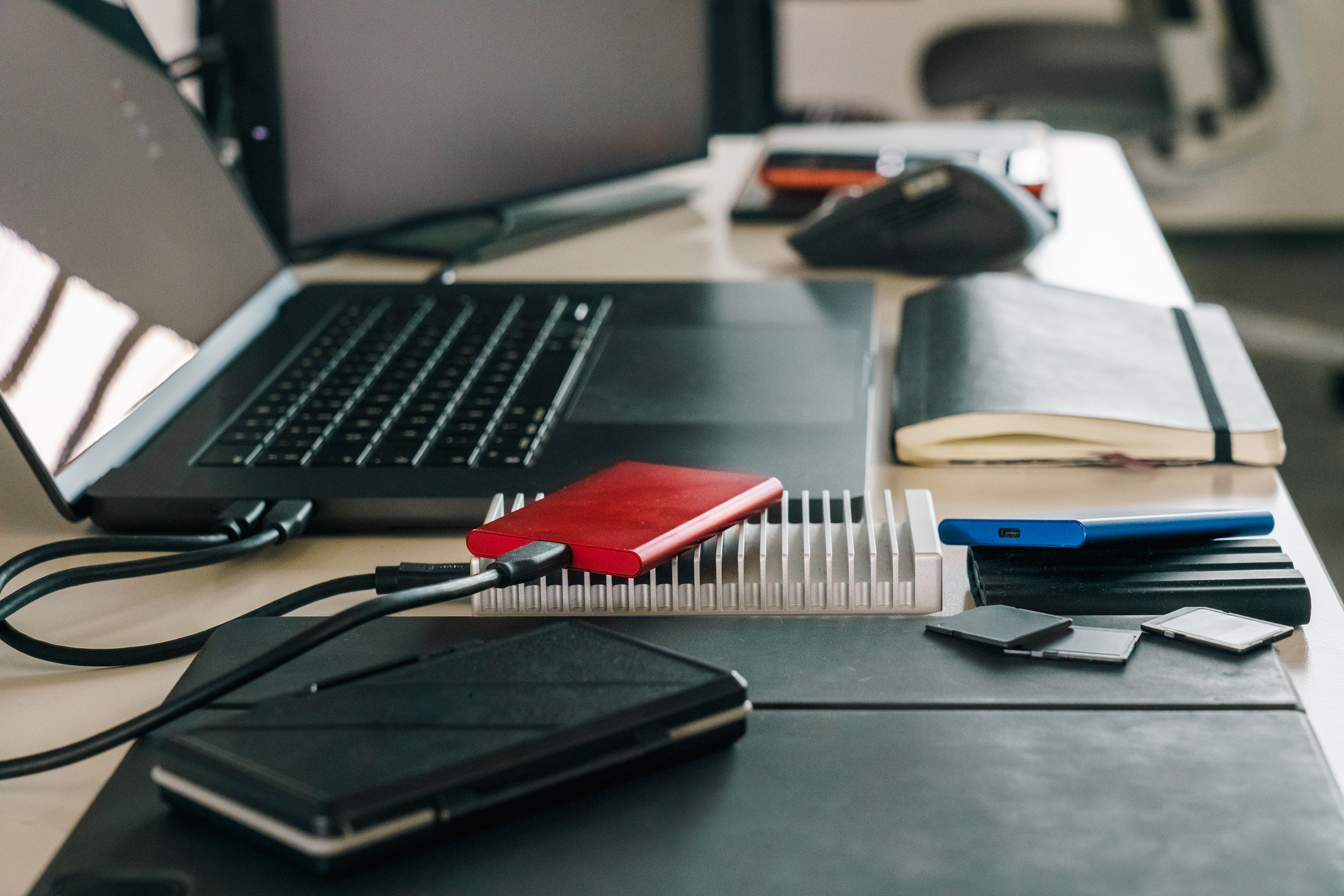 Modern office desk featuring laptop, external drives, and various tech accessories for efficient workflow.