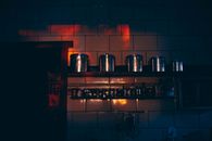 Low angle of stainless steel canisters placed in row on shelf in dark kitchen with tile walls