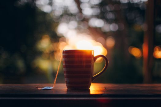 日落时分，木桌上的一杯热茶，营造出宁静而温暖的氛围