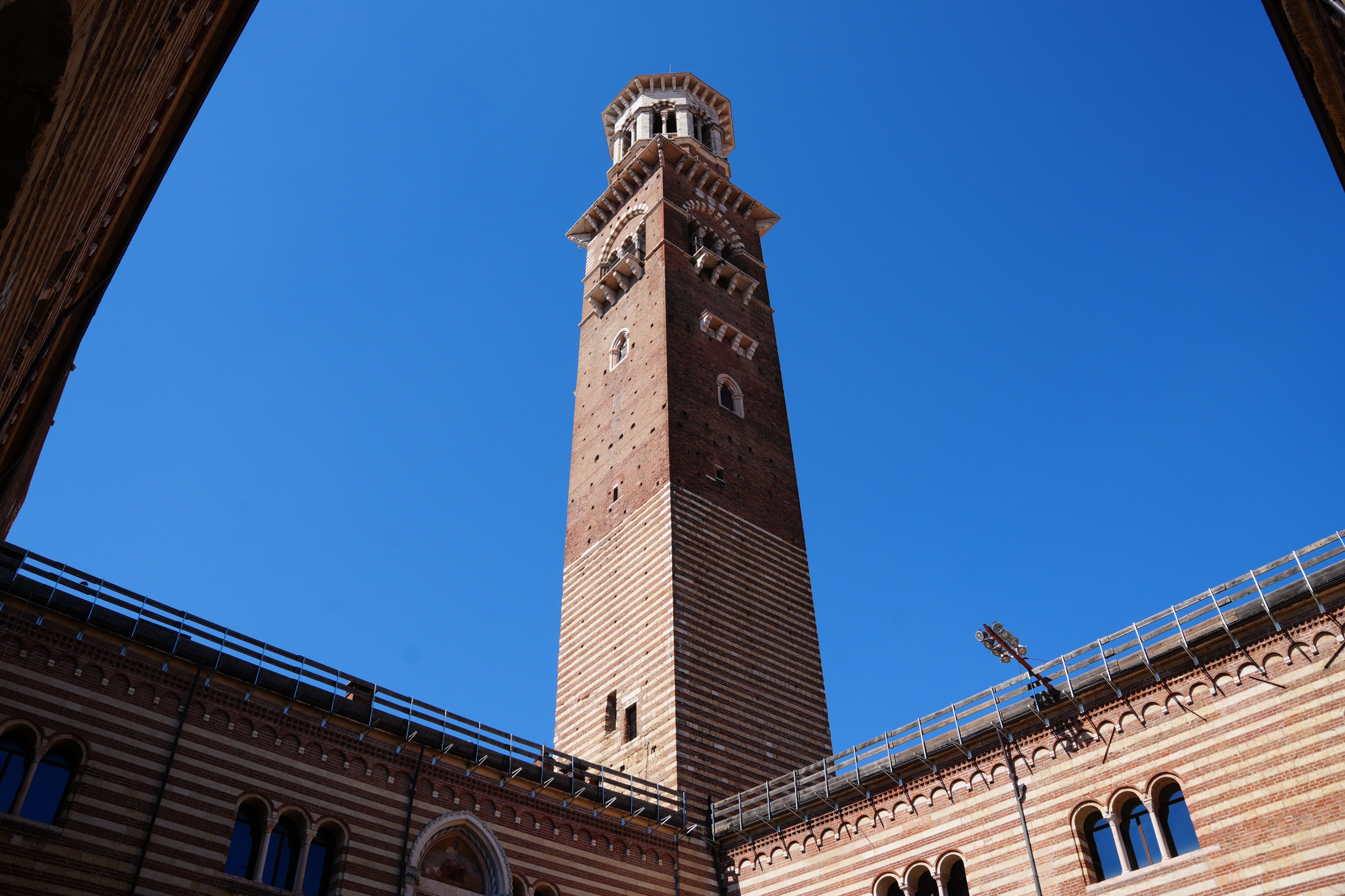 The iconic Torre dei Lamberti, a medieval tower in Verona, against a clear blue sky.