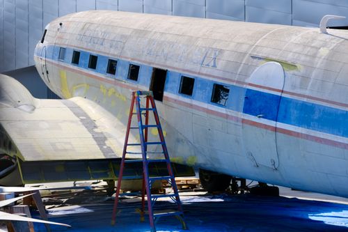 Free A vintage aircraft undergoing restoration outdoors in Los Angeles, featuring a blue ladder. Stock Photo