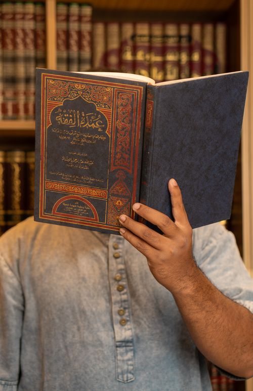 Free A man reading an Arabic book in a library, reflecting education and culture. Stock Photo