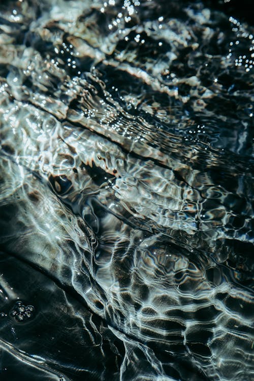 From above of glare on transparent water of clean pond as abstract background