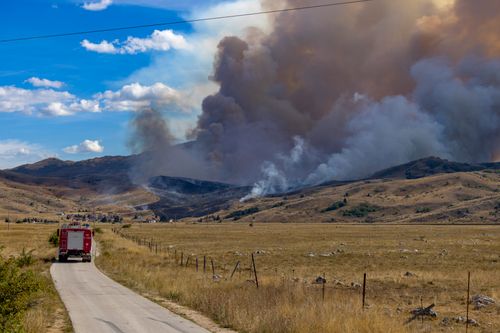 Free A fire truck travels on a dirt road towards a forest fire in Zvirnjača, Bosnia. Stock Photo