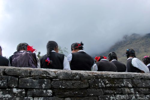 Free Girls in school uniforms sitting outdoors with foggy mountains in the background. Stock Photo