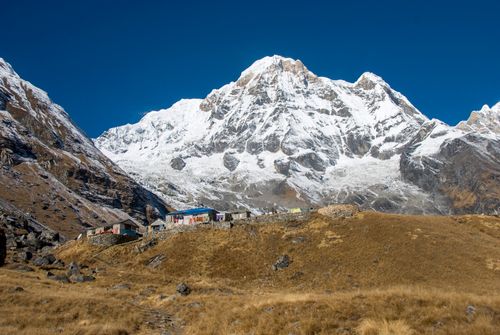 Free Breathtaking view of the snow-capped Annapurna mountains with rustic huts in the foreground. Stock Photo