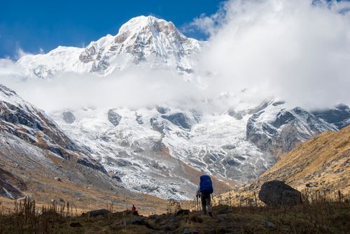 Free A hiker approaches the snow-capped Annapurna mountain range under a clear blue sky. Stock Photo