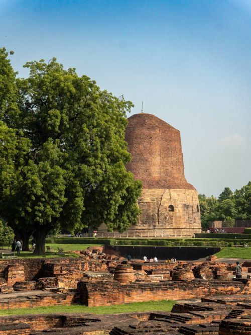 Free Scenic view of the ancient Dhamek Stupa surrounded by lush greenery in Sarnath, Varanasi. Stock Photo