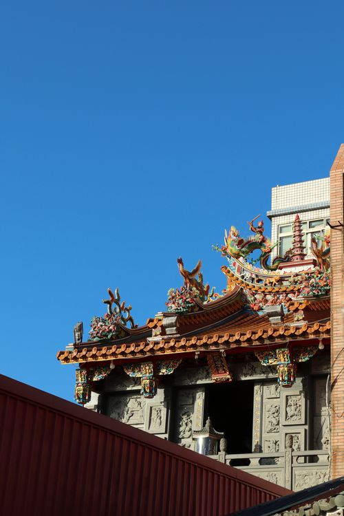 Free Intricately designed temple rooftop with vibrant decorations and clear blue sky backdrop. Stock Photo