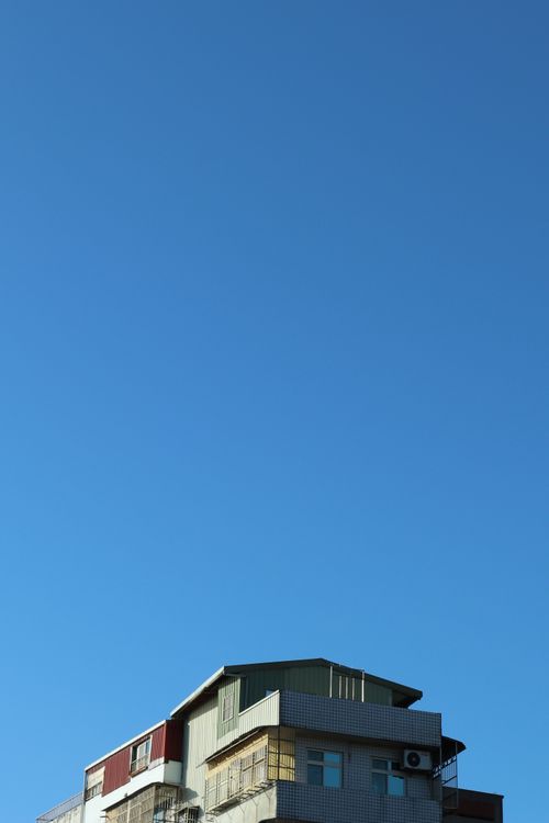 Free An urban building with unique architecture set against a clear blue sky, offering ample copyspace. Stock Photo