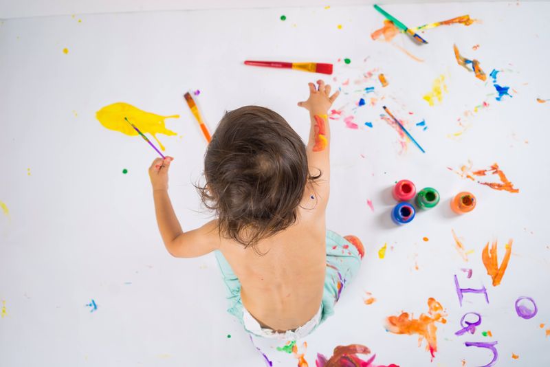 A child finger painting on a large canvas