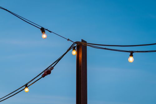 Free Warm glowing string lights set against a clear twilight sky, creating a serene ambiance. Stock Photo