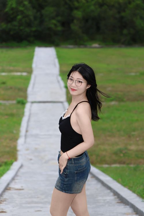 Free Young woman posing confidently on a path in Hefei, Anhui. Nature background, casual summer fashion. Stock Photo