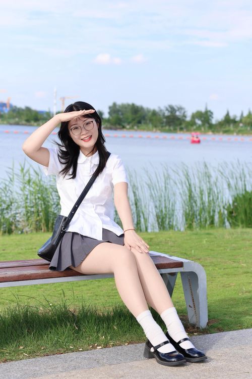 Free A cheerful young woman enjoys a sunny day sitting by the serene lake in Hefei, Anhui, China. Stock Photo
