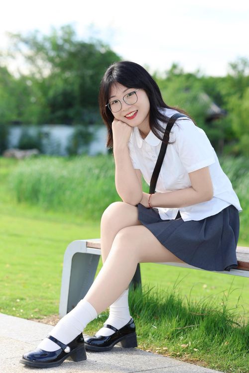 Free A young woman in casual attire enjoys a sunny day on a park bench in Hefei. Stock Photo