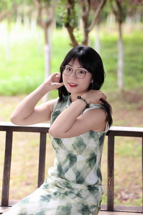 Free Portrait of a young woman in a green dress sitting outdoors, smiling. Stock Photo