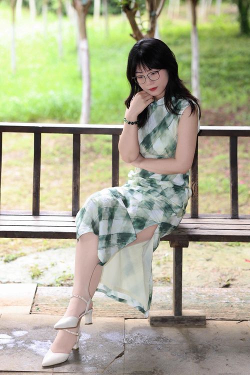 Free Stylish woman in a green plaid dress sitting on a bench in Hefei, China, during a bright day. Stock Photo