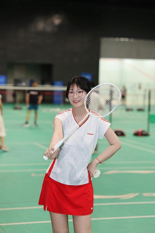 Free Young woman in sports attire playing badminton indoors, showcasing an athletic pose on a green court. Stock Photo