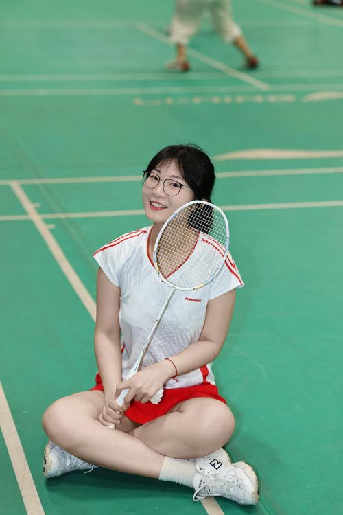 Free Young woman on a badminton court smiling, holding racket. Indoor sports location. Stock Photo
