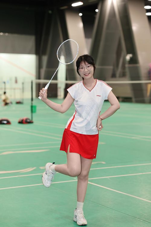 Free Smiling young woman with badminton racket posing on an indoor court, ready for play. Stock Photo
