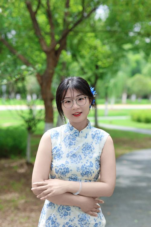 Free A woman in a cheongsam poses outdoors against a lush green background. Stock Photo