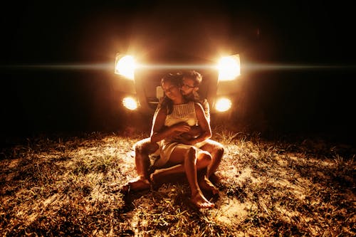 Sensual young couple cuddling near car during picnic at night