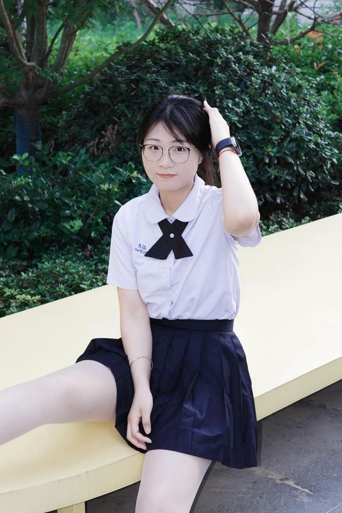 Free Young woman sitting on a bench in a park in Hefei, China, wearing a school uniform. Stock Photo
