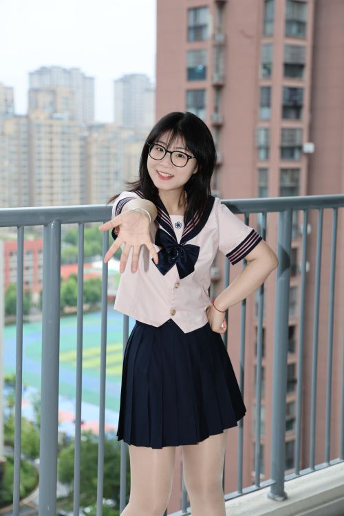 Free Smiling young woman in a school uniform stands on a balcony in Hefei, China, with a cityscape view. Stock Photo