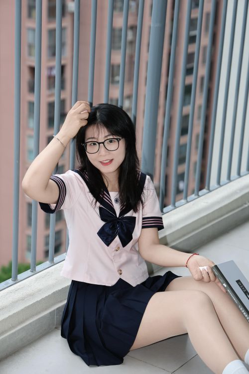 Free Asian woman in sailor uniform sits outdoors with buildings in background, Hefei, China. Stock Photo