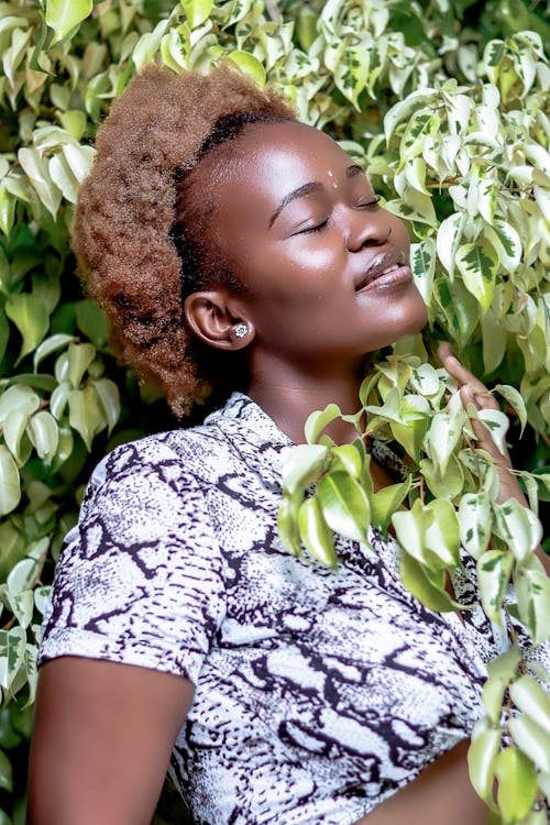 微笑的非洲裔美國老婦，閉著眼睛，在綠色的植物中放鬆
